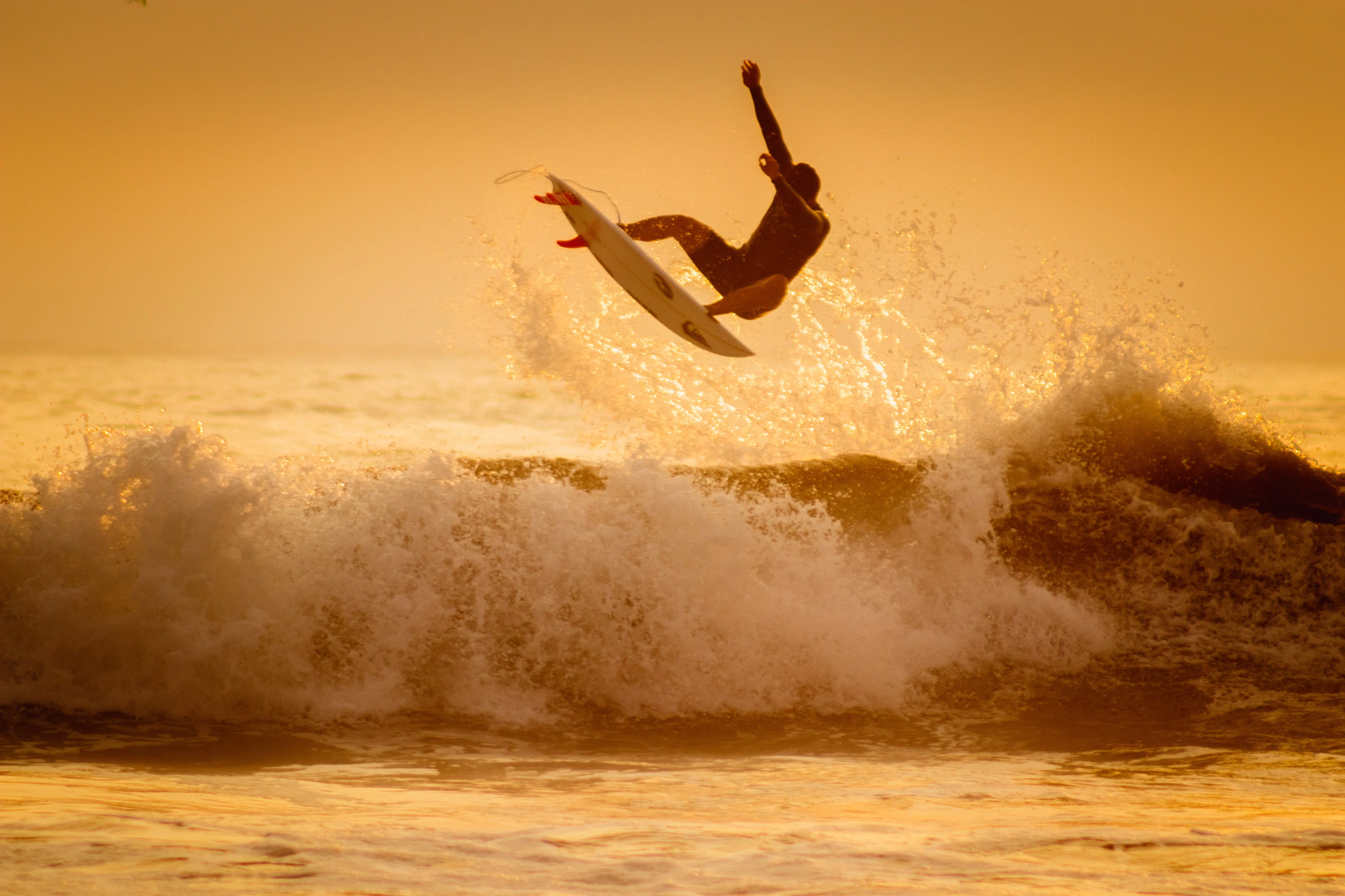 sepia photo of a surfer maneuvering in the air over a wave