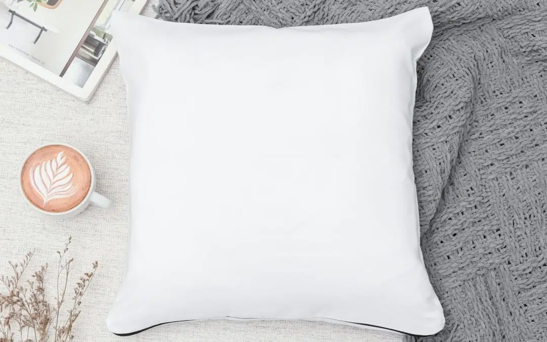 coffee mug next to a white pillow on a bed